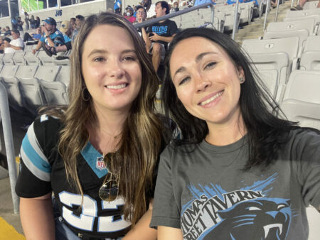 Two women sitting at a game smiling.