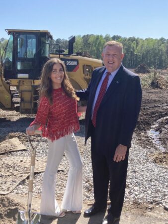 a woman and man dressed formal and a construction site smiling.