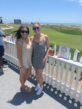 Two women smiling at a golf tournament.