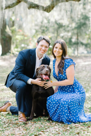A couple smiling with their brown lab.