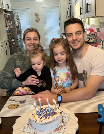 Family smiling in front of birthday cake.