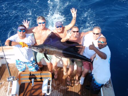 6 men posing with large swordfish.