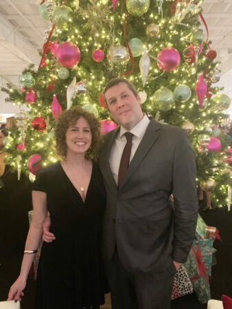 Man and woman posing in front of a Christmas tree.