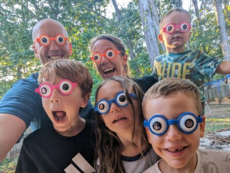 A family smiling with googly eye glasses on.