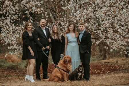 A family with two dogs all smiling in nature dressed formal.