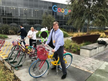 Man outside of google building on a bike smiling.