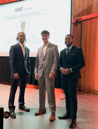 three men posing in front of screen at American Advertising Awards event