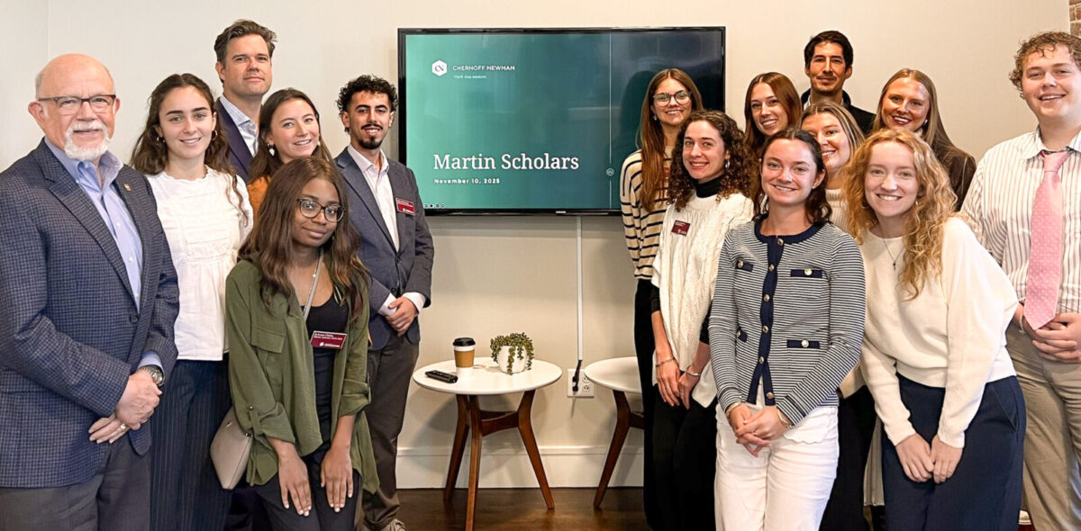 A group of students and faculty members posing together in front of a screen displaying "Martin Scholars" during a ceremony.