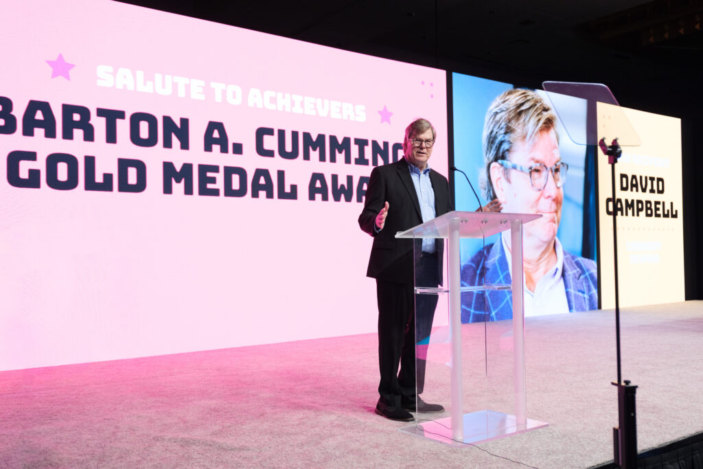 CEO David Campbell on stage behind a podium to receive the Barton A Cummings Gold Medal Award