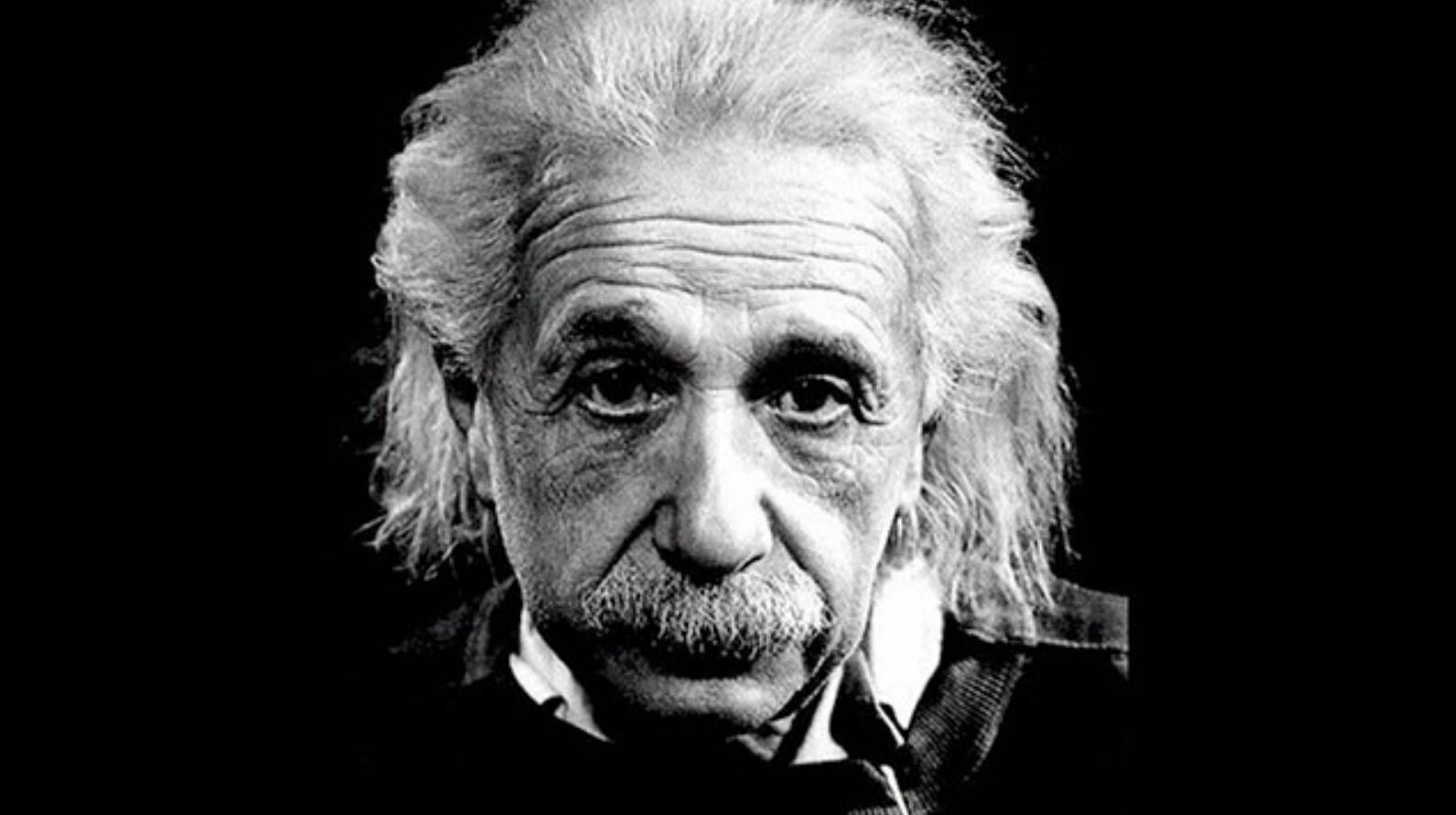 A back and white photo of Einstein's face on a black background